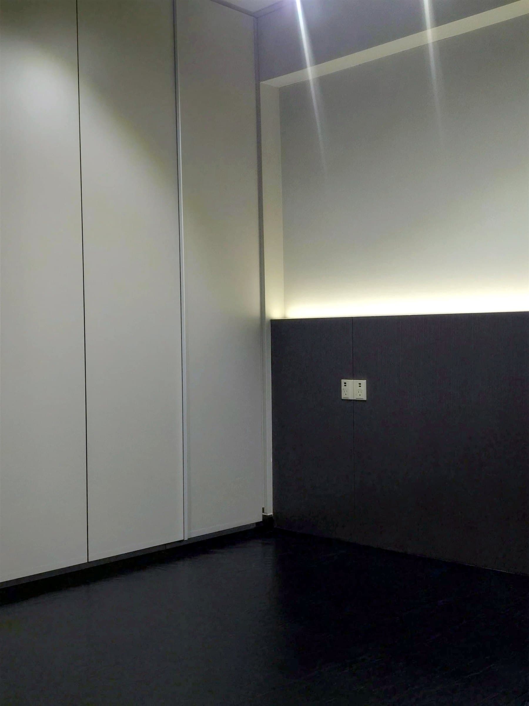 Full-height wardrobe run with a concealed LED cove light above a dark lower panel