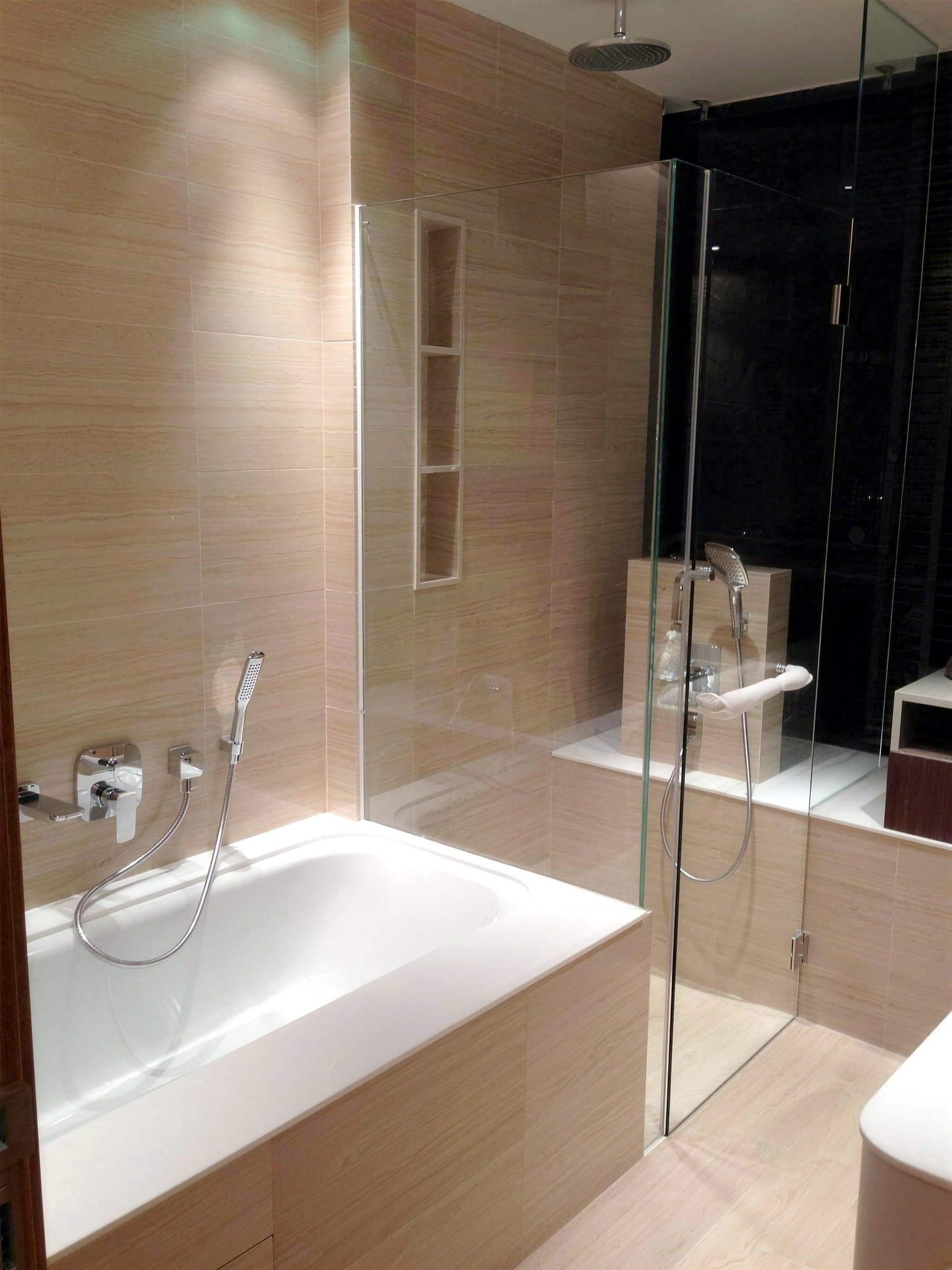Bathroom with stone-clad walls, bathtub and glass shower screen