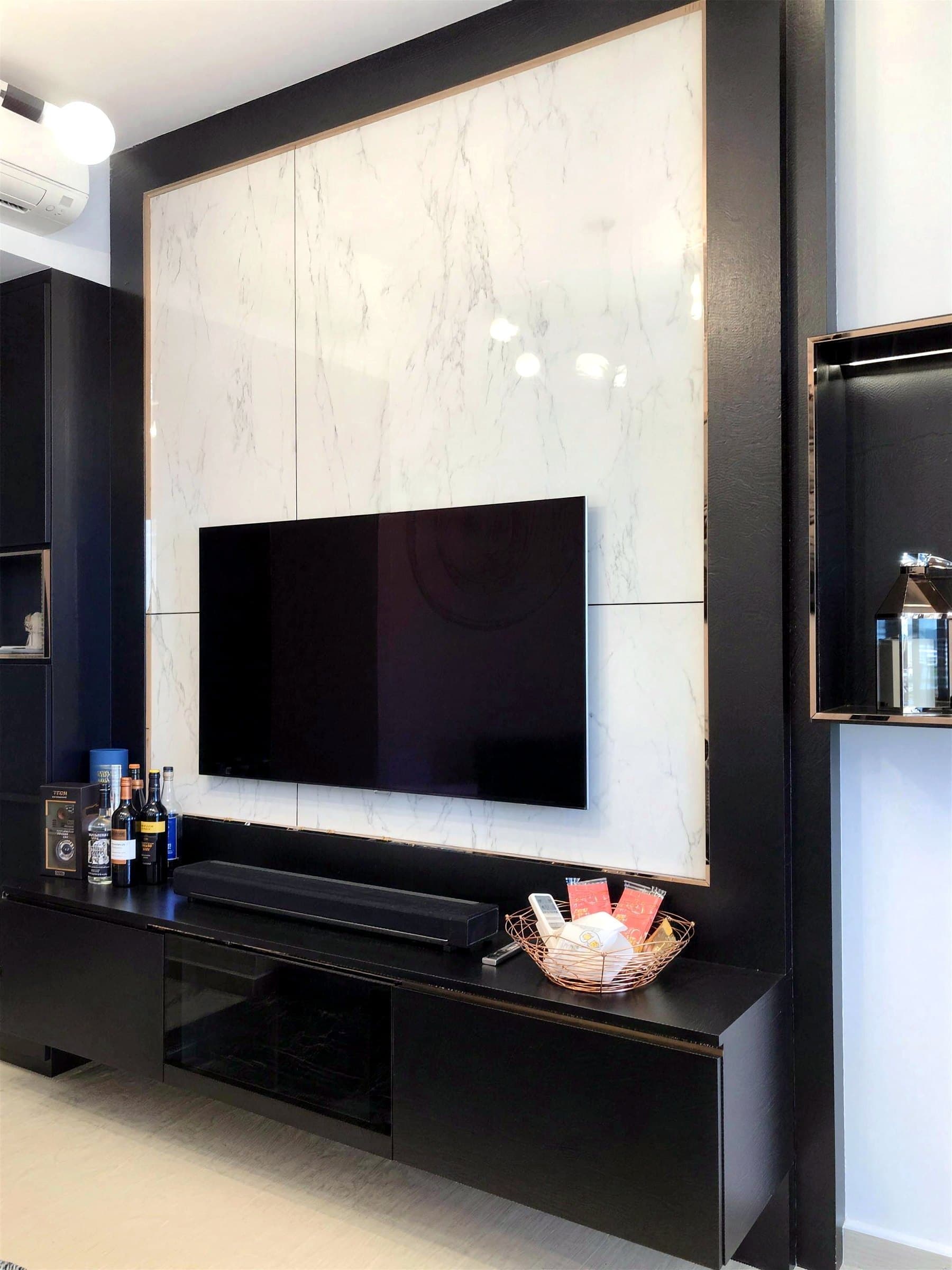 Brownstone living room with a marble-panelled TV wall and black cabinetry with rose-gold trim