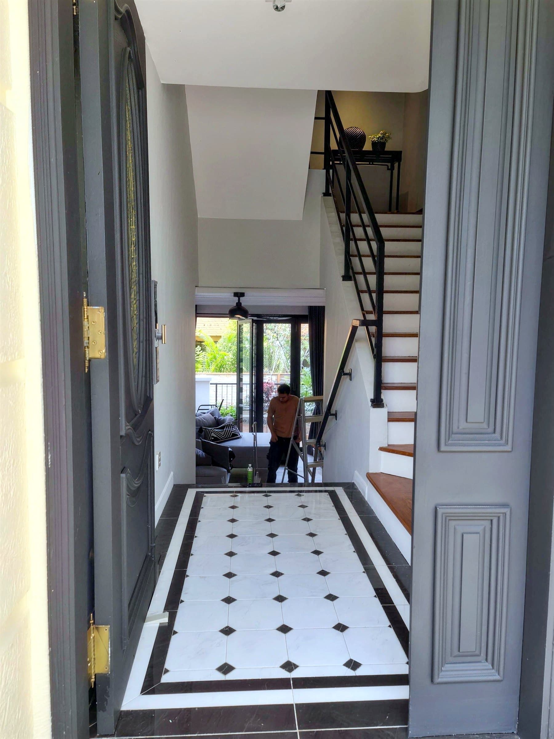 Entry with black-and-white marble diamond floor tile and black stair railing