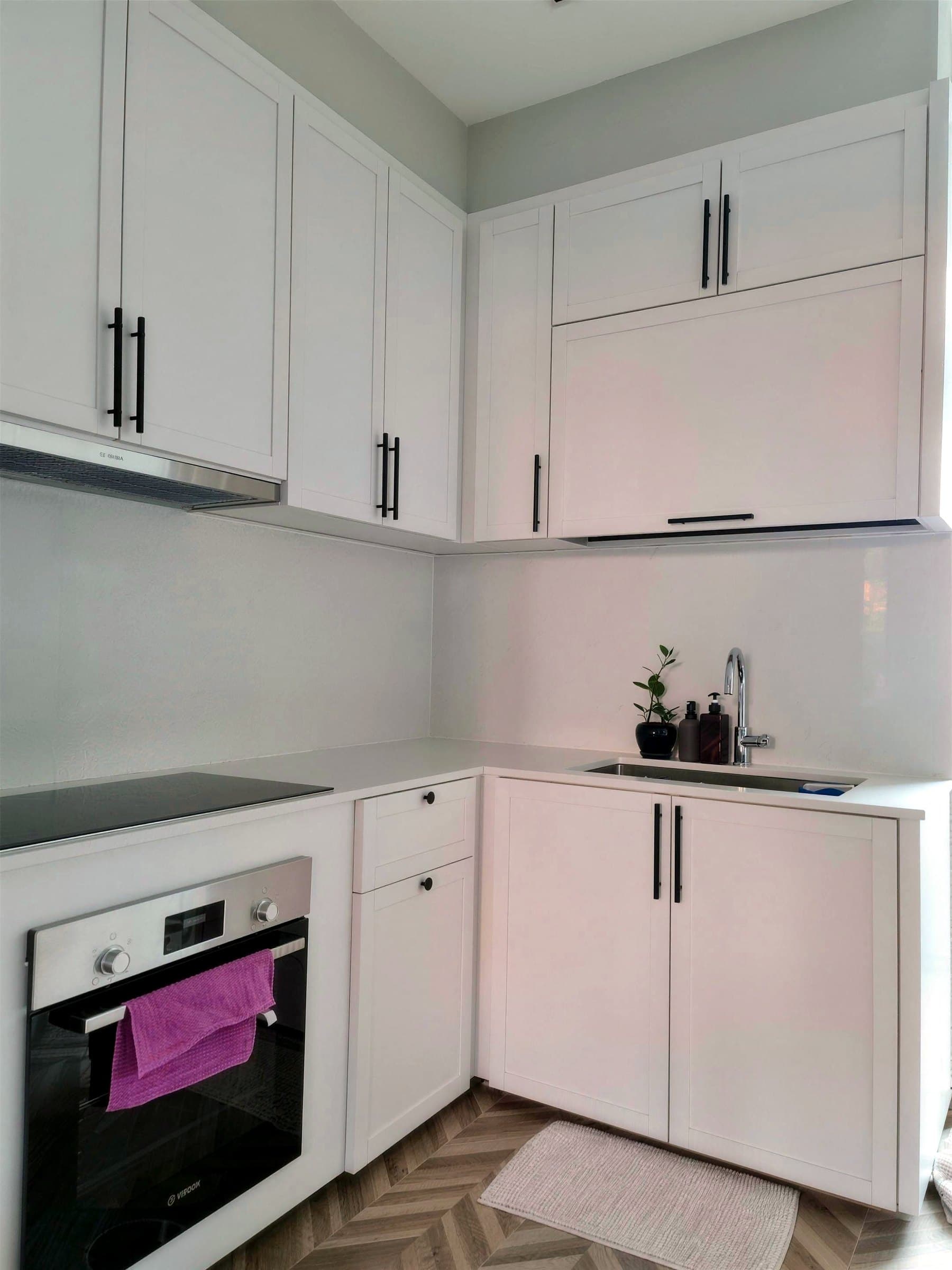 White shaker kitchen with integrated oven and herringbone floor tile