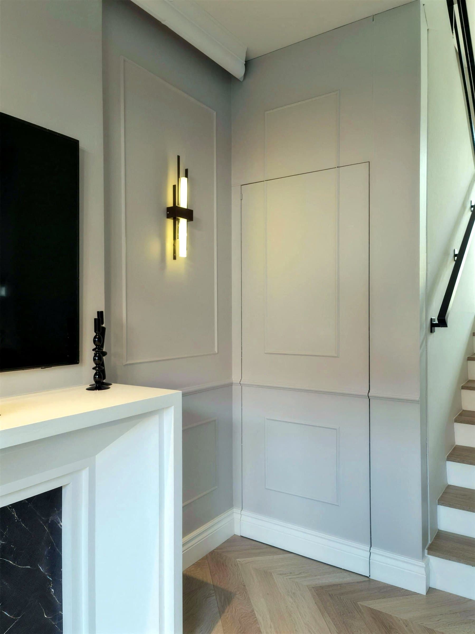 Wall panelling with a black art-deco linear sconce beside the stairs