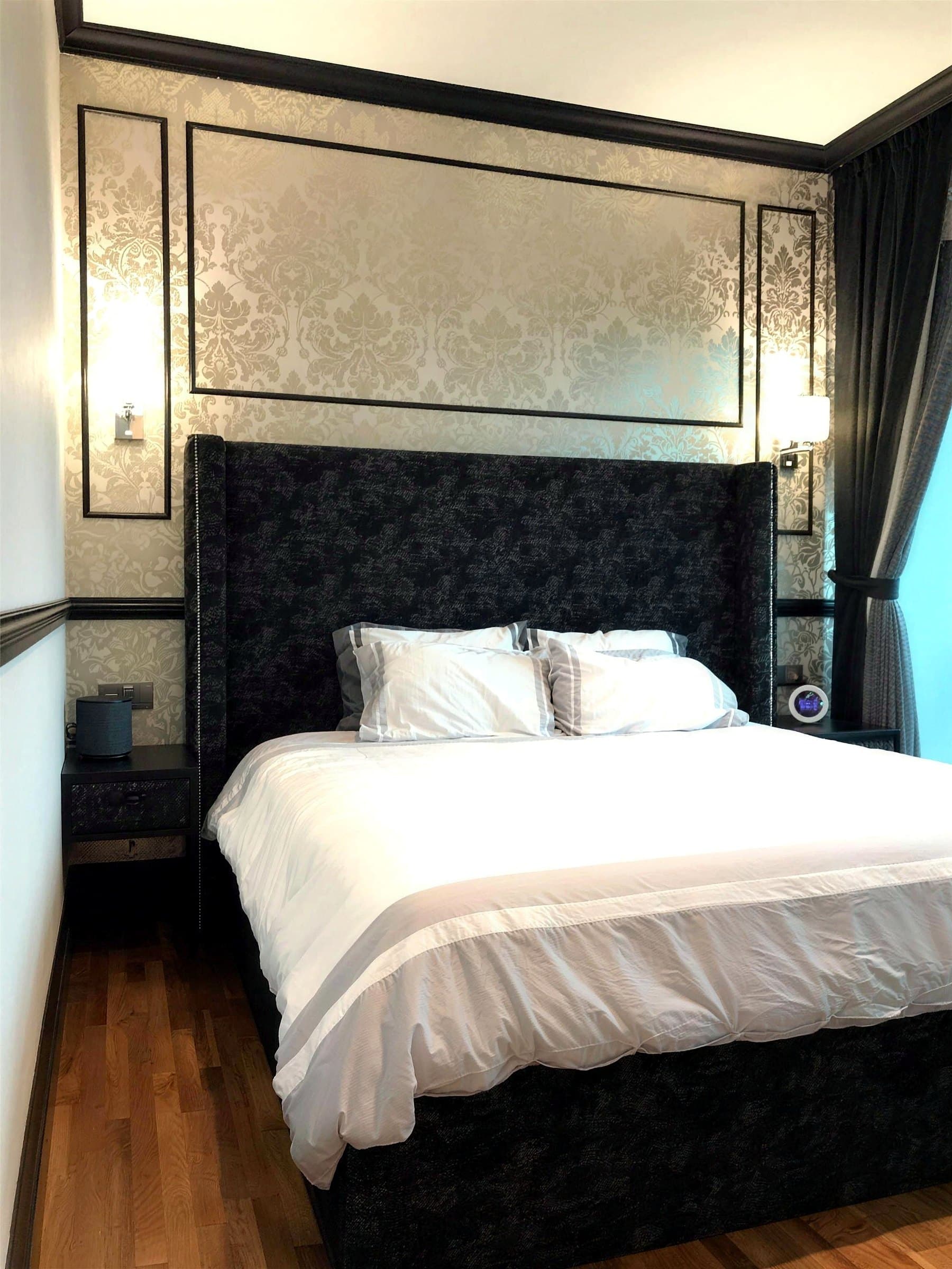 Second bedroom with damask wallpaper and a channel-tufted headboard-to-ceiling cove